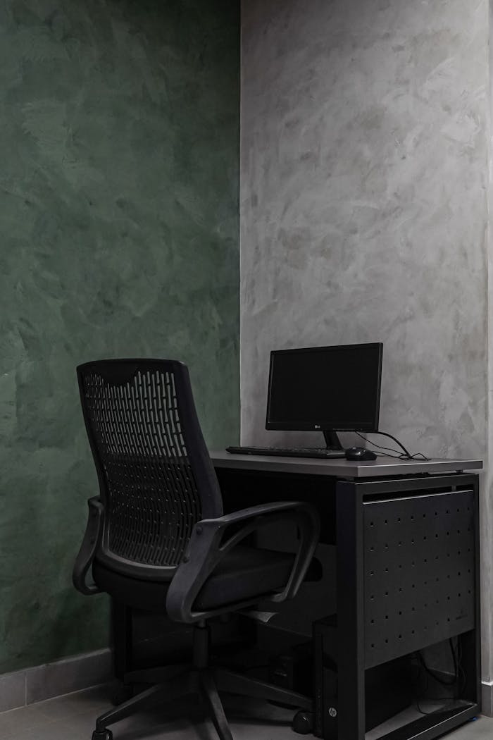 services-bg Simple modern office interior with a mesh chair and desk against textured walls.