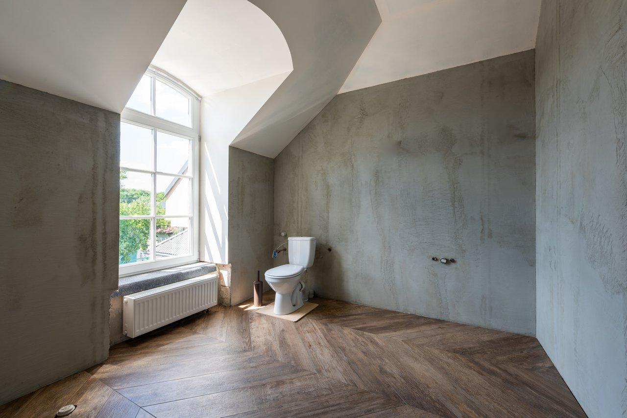 Spacious minimalist bathroom featuring modern design and large window with natural light.